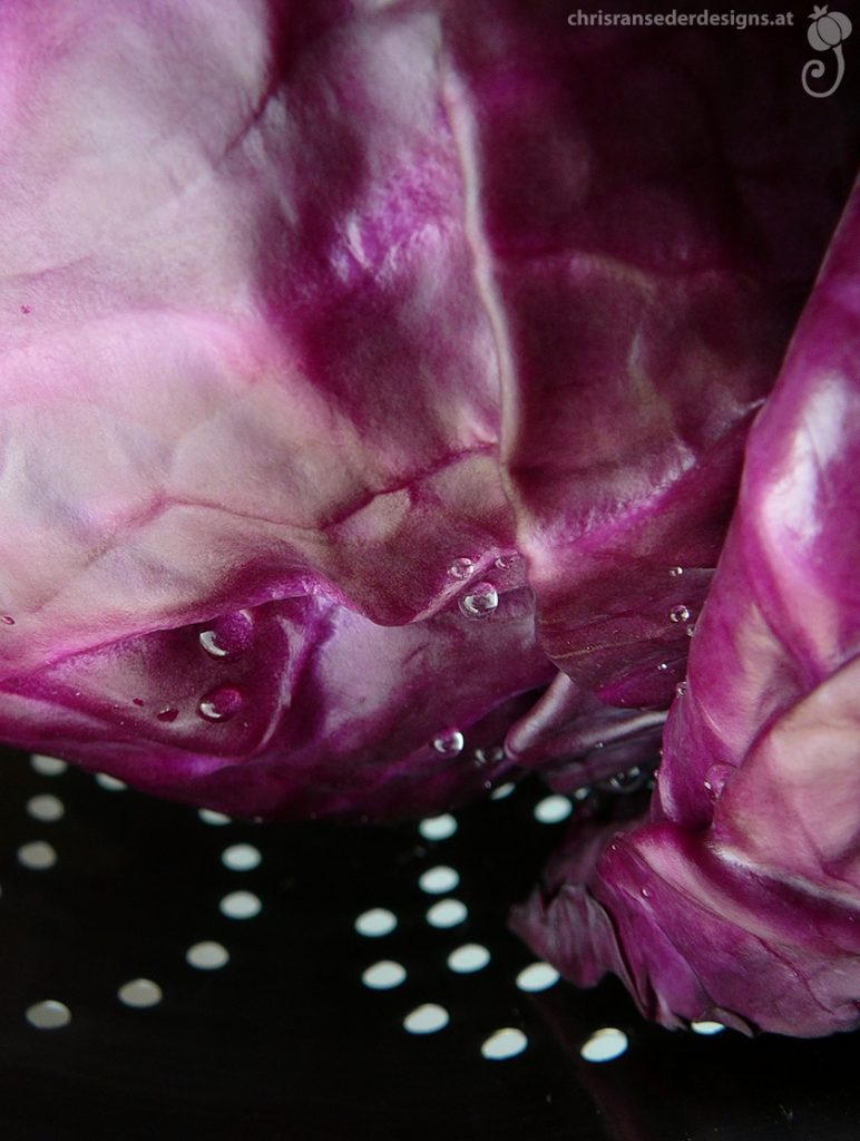 Closeup of a red cabbage in a sieve. | Nahaufnahme eines Happels Rotkraut in einem Sieb liegend.