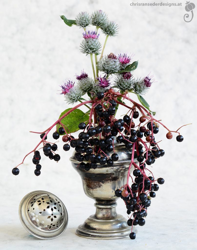 Bouquet of elderberries and burdock in a silver sugar sprinkler. | Strauß aus Holunterbeeren und Kletten in einem silbernen Zuckerstreuer.