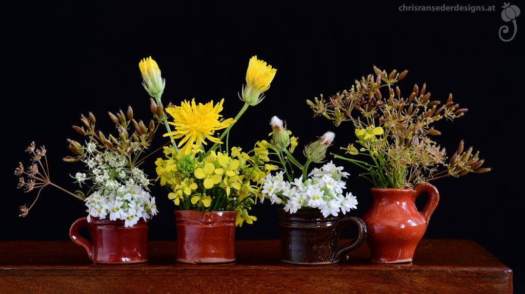 Vier Tontöpfchen mit gelben und weißen Blumen. | For tiny pots made of clay filled with white ans yellow flowers.