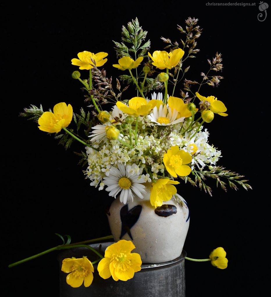Ein üppiges Sträußchen aus gelben und weißen Wiesenblumen in einer kugeligen Vase. | A tightly packed bunch of white and yellow meadow flowers in a bulbous little vase. 